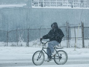 A man rides his bicycle through the snow in Muskegon, Mich. on Wednesday, April 4, 2018.  A spring storm dumped more than a foot of snow in parts of Michigan's northern Lower Peninsula and is blamed for creating hazardous road conditions.
