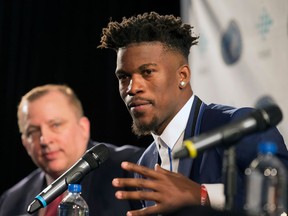 FILE - In this June 29, 2017 file photo, Jimmy Butler speaks as Minnesota Timberwolves head coach Tom Thibodeau, left, looks on during an introductory news conference in Bloomington, Minn. Butler is nearing a return to action, with four critical games to go for the team in the regular season. He told reporters after practice on Tuesday, April 3, 2018 that he's "this close" to being back on the court. Coach Thibodeau said Butler was a full participant in the workout. His surgically repaired right knee would be evaluated again on Wednesday.
