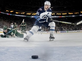 Winnipeg Jets' Mark Scheifele (55) scores after breaking away from Minnesota Wild's Mikael Granlund (64) to score an empty-net goal during the third period of Game 4 of an NHL hockey first-round playoff series Tuesday, April 17, 2018, in St. Paul, Minn.