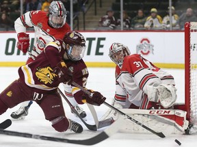 Minnesota-Duluth's Peter Krieger (25) tries to get the puck in the net against Ohio State goalie Tommy Nappier (37) during the first period of a semifinal in the NCAA men's Frozen Four hockey tournament Thursday, April 5, 2018, in St. Paul, Minn.