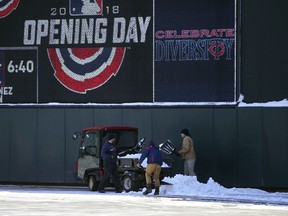 Grounds crew workers remove the remaining snow from Tuesday's storm in right field at Target Field in Minneapolis Wednesday, April 4, 2018, in preparation for Thursday's baseball home opener between the Minnesota Twins and the Seattle Mariners.