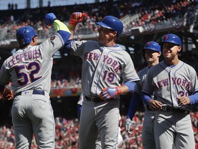 New York Mets right fielder Jay Bruce (19) is greeted by teammates Yoenis Cespedes (52), Michael Conforto (30) and Brandon Nimmo (9), who all scored on Bruce's grand slam against Washington Nationals relief pitcher Brandon Kintzler, in the seventh inning of home opener baseball game, at Nationals Park, Thursday, April 5, 2018 in Washington.