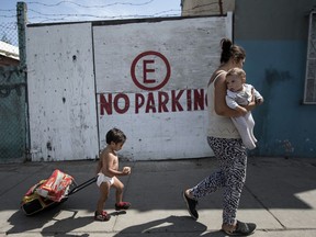 A Honduran migrant who is traveling with a caravan of Central American migrants walks with her two children to a shelter in Tijuana, Mexico, Wednesday, April 25, 2018. The group of mainly Central American migrants are planning to request asylum, either in the United States or Mexico.