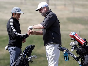 In this April 5, 2018 photo, 61-year-old Bellevue University golf team member Don Byers, right, helps tape the hand of teammate Andre Becerra, during practice at the Platteview Golf Club in Bellevue, Neb. Byers mixes easily with his teammates. He said being old enough to be their father, or grandfather, hasn't necessarily given him privilege. "Being a freshman," he said, "I have to get their bags out of the van now and then.