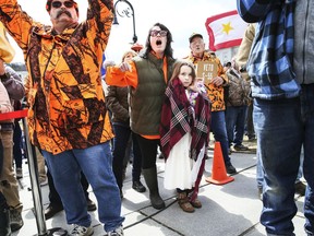 Gun rights activist Deserae Morin, with seven-year old daughter Maple, facing center, shouts as Vermont Republican Gov. Phil Scott speaks before signing the first significant gun restrictions bills in the state's history during a ceremony on the steps of the Statehouse in Montpelier, Vt., Wednesday, April 11, 2018.