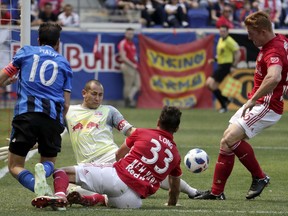 New York Red Bulls goalkeeper Luis Robles, center left, gets helped by midfielder Aaron Long (33) and defender Tim Parker (26) while defending against Montreal Impact midfielder Ignacio Piatti (10) during the first half of a soccer match, Saturday, April 14, 2018, in Harrison, N.J.