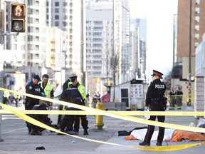 Police secure an area around a covered body in Toronto after a van mounted a sidewalk crashing into a number of pedestrians on Monday, April 23, 2018.