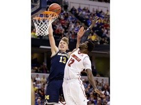 FILE - In this Sunday, March 19, 2017, file photo, Michigan forward Moe Wagner (13) shoots over Louisville forward Mangok Mathiang (12) during the second half of a second-round game in the men's NCAA college basketball tournament in Indianapolis.  Wagner has decided to sign with an agent and enter the NBA draft. The Michigan big man announced his plans Saturday, April 14, 2018 with an essay written for The Players' Tribune.