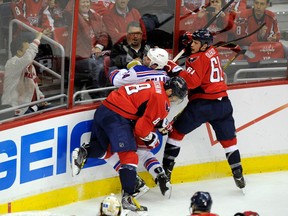 FILE - In this May 13, 2013, file photo, New York Rangers right wing Ryan Callahan (24) gets checked into the boards by Washington Capitals left wing Alex Ovechkin (8), from Russia, and Steve Oleksy during the second period of Game 7 of a first-round NHL Stanley Cup playoff hockey series in Washington. 2013 was the third year in a row the two teams met in the playoffs.