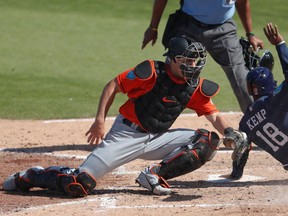 FILE - In this March 5, 2018, file photo, Houston Astros' Tony Kemp (18) beats the tag from Miami Marlins catcher J.T. Realmuto to score on an Alex Bregman base hit in the fourth inning of a spring training baseball game in West Palm Beach, Fla. Realmuto has been activated from the disabled list to make his season debut, against the New York Yankees. Realmuto was behind the plate Tuesday night, April 17, for the last-place Marlins, batting fifth. He had been sidelined by a bruised back since March 11.