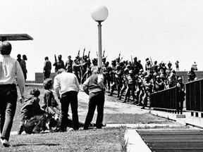 FILE - In this May 4, 1970 file photo, a group of youths gather around a wounded person as Ohio National Guardsmen, wearing gas masks, hold their weapons in the background, on the Kent State University campus in Kent, Ohio. Members of the Guards killed four students and injured nine during a campus protest against the Vietnam War.