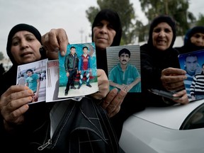 In this Thursday, April 26, 2018 photo, women show photos of their relatives at Nineveh Criminal Court, one of two counterterrorism courts in Iraq where suspected Islamic State militants and their associates are tried, in Tel Keif, Iraq. Iraq is holding huge numbers of detainees on suspicion of ties to the Islamic State group _ around 11,000, according to Iraqi officials _ and they are being rushed through counterterrorism courts in trials that raise serious questions over whether justice is being done.