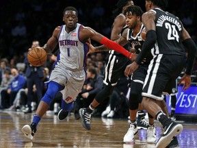 Detroit Pistons guard Reggie Jackson (1) drives to the basket past Brooklyn Nets guard D'Angelo Russell (1) and Nets forward Rondae Hollis-Jefferson (24) during the first half of an NBA basketball game Sunday, April 1, 2018, in New York.