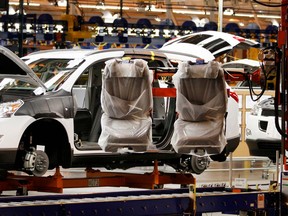 FILE - In this Oct. 3, 2008, file photo, assembly line worker Melvin Matthews, right, uses a large robotic machine to install front seats in a new 2009 Chevrolet Traverse at the GM Spring Hill Manufacturing Plant, in Spring Hill, Tenn. General Motors Corp. is adding a shift at the Tennessee factory that makes GMC and Cadillac SUVs, putting about 700 people to work. The Spring Hill plant now employs about 2,600 hourly workers on two shifts. They make the GMC Acadia and Cadillac XT5.