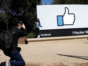 FILE- In this March 28, 2018, file photo, visitors take photos in front of the Facebook logo at the company's headquarters in Menlo Park, Calif. Facebook reports earnings Wednesday, April 25.