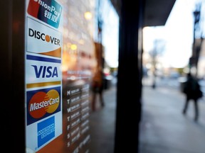 FILE- In this Jan. 31, 2018, file photo, credit card logos are posted to the door of a business in Atlanta. On Friday, April 6, the Federal Reserve releases its February report on consumer borrowing.