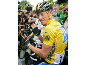 FILE - In this July 24, 2005, file photo, overall leader Lance Armstrong, of Austin, Texas, surrounded by press photographers, gestures seven, for his seventh straight win in the Tour de France cycling race, prior to the start of the 21st and final stage of the race, between Corbeil-Essonnes, south of Paris, and the French capital. Armstrong, on Thursday, April 19, 2018, has reached a $5 million settlement with the federal government in a whistleblower lawsuit that could have sought $100 million in damages from the cyclist who was stripped of his record seven Tour de France victories after admitting he used performance-enhancing drugs throughout much of his career.