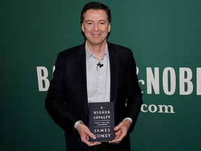 FILE - In this April 18, 2018 file photo, former FBI director James Comey poses with his book "A Higher Loyalty" at a Barnes & Noble book store in New York. Flatiron Books announced Tuesday that sales topped 600,000 copies, a number that includes print, audio and e-books. The former FBI director's memoir has been one of the year's most anticipated releases.
