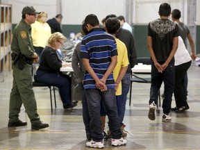 FILE - In this June 18, 2014, file photo, boys wait in line to make a phone call as they are joined by hundreds of mostly Central American immigrant children that are being processed and held at the U.S. Customs and Border Protection Nogales Placement Center in Nogales, Ariz. The Associated Press has learned that a Senate subcommittee has found that the government risks placing migrant children in the custody of human traffickers because federal agencies have delayed crucial reforms needed to keep the children safe.