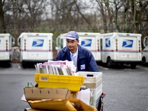 FILE - In this Feb. 7, 2013 file photo, U.S. Postal Service letter carrier Michael McDonald gathers mail to load into his truck before making his delivery run in the East Atlanta neighborhood, in Atlanta. After weeks of railing against online shopping giant Amazon, President Donald Trump signed an executive order Thursday, April 12, 2018, creating a task force to study the United States Postal System.