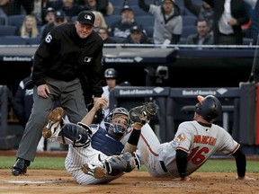 New York Yankees catcher Gary Sanchez, front left, holds onto the ball after tagging out Baltimore Orioles' Trey Mancini (16) during the first inning of a baseball game, Thursday, April 5, 2018, in New York. Mancini was initially ruled safe on the play but the call was overturned after an instant replay review.