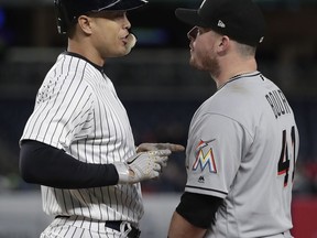 New York Yankees' Giancarlo Stanton, left, speaks with Miami Marlins first baseman Justin Bour (41) after walking during the fourth inning of a baseball game, Monday, April 16, 2018, in New York.