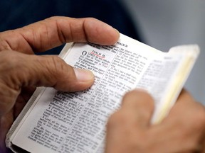 FILE- In this Sept. 3, 2017, file photo, a man holds a bible during service at Christ United Church in the aftermath of Hurricane Harvey in Cypress, Texas. Bible sales would not be banned in California under proposed state legislation, contrary to widely shared claims by multiple online sites.