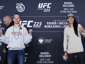 CORRECTS TO NAMAJUNAS NOT NAMAJUNA - UFC women's straw weight champion Rose Namajunas, left, poses for a photograph with upcoming opponent Joanna Jedrzejczyk, Thursday, April 5, 2018, during UFC 223's media day at the Barclay's Center in New York, ahead of their fight on Saturday, April 7. UFC president Dana White, left, ducks out of the photo.