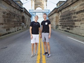 In this Sept. 23, 2017 photo provided by PJ Painter and Ryan Bedinghaus, PJ, right, and Ryan hold hands in front of the John A. Roebling Suspension Bridge in Cincinnati, Ohio, for an engagement photo. Traditional weddings are deeply rooted in gender-based rituals. But the growing LGBTQ wedding industry is coming up with new approaches. Many couples are engaging with centuries of tradition but crafting their own way to the altar.