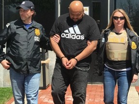 This photo provided by the DEA, Miguel Angel Corea Diaz, center, the alleged East Coast leader of MS-13, is lead by Drug Enforcement Administration officers, Wednesday, April 18, 2018 in Baltimore.  DEA agents have brought Diaz to New York to face murder conspiracy and drug-trafficking charges. Prosecutors say Diaz ordered beatings and killings and directed the gang's drug operations in New York, New Jersey, Maryland, Texas and elsewhere. (Drug Enforcement Administration via AP)