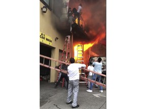 In this Monday, April 9, 2018 photo, girls flee a second-story dance studio onto a balcony as a roaring fire engulfs their building in Edgewater, N.J.    About 15 girls were treated for minor injuries, Mayor Michel Joseph McPartland said.