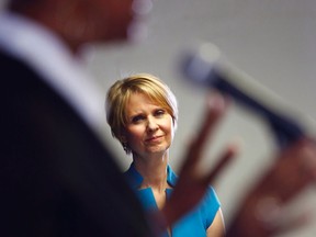 FILE - In this March 20, 2018 file photo, candidate for New York governor Cynthia Nixon, right, running against Gov. Andrew Cuomo, listens as she is introduced during a campaign stop at the Bethesda Healing Center church, in the Brooklyn borough of New York. New York City's massive public housing system is finally getting attention from politicians after years of neglect and a winter of heating failures, with both Nixon and Cuomo recently touring a public housing complex in Brooklyn.