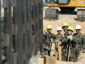 FILE - In this Monday, June 5, 2006, file photo, Utah National Guard troops from the 116th Construction Equipment Support Company, the first National Guard unit along the border as part of Operation Jump Start, prepare to extend a wall along the U.S.-Mexico border in San Luis, Ariz. In 2018, the U.S. National Guard faces a vastly different environment than it did on its last two deployments to the border with Mexico, with far fewer illegal crossings and more Central Americans than Mexicans coming.