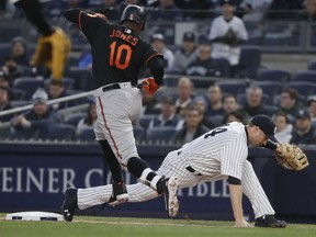 New York Yankees first baseman Neil Walker (14) keeps his foot on the bag for the out after grabbing a wide throw on a ball hit by Baltimore Orioles' Adam Jones (10) during the first inning of a baseball game Friday, April 6, 2018, in New York.