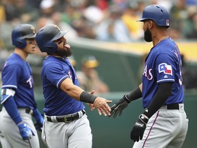 Texas Rangers' Rougned Odor, center, celebrates with Nomar Mazara, right, after both scored against the Oakland Athletics in the second inning of a baseball game Thursday, April 5, 2018, in Oakland, Calif.