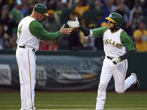 Oakland Athletics' Jed Lowrie, right, is congratulated by third base coach Matt Williams after hitting a home run off Chicago White Sox pitcher Miguel Gonzalez during the first inning of a baseball game Tuesday, April 17, 2018, in Oakland, Calif.