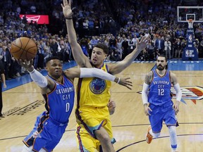 Oklahoma City Thunder guard Russell Westbrook (0) goes to the basket in front of Golden State Warriors guard Klay Thompson, center, during the first half of an NBA basketball game in Oklahoma City, Tuesday, April 3, 2018. Thunder center Steven Adams is at right.