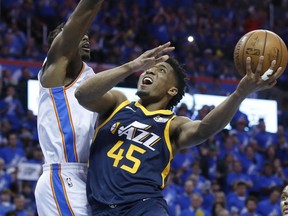 Utah Jazz guard Donovan Mitchell (45) shoots as Oklahoma City Thunder forward Jerami Grant, left, defends in the second half of Game 1 of an NBA basketball first-round playoff series in Oklahoma City, Sunday, April 15, 2018.