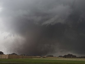 FILE - In this Monday, May 20, 2013 file photo, a tornado moves past homes in Moore, Okla. Emergency officials in Oklahoma, Texas and Kansas are bracing for the start of what's historically the most active time of year for tornadoes while also facing wildfire threats because of severe drought conditions.