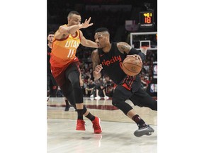Portland Trail Blazers guard Damian Lillard, right, drives to the basket on Utah Jazz guard Dante Exum during the first half of an NBA basketball game in Portland, Ore., Wednesday, April 11, 2018.