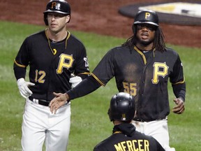 Pittsburgh Pirates' Josh Bell (55) and Corey Dickerson (12) return to the dugout after scoring on a single by Colin Moran off Cincinnati Reds starting pitcher Luis Castillo in the third inning of a baseball game in Pittsburgh, Friday, April 6, 2018.