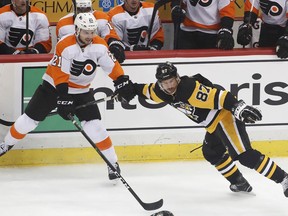Philadelphia Flyers' Scott Laughton (21) hangs onto Pittsburgh Penguins' Sidney Crosby (87) during the first period in Game 1 of an NHL first-round hockey playoff series in Pittsburgh, Wednesday, April 11, 2018.