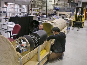 In this photo made on Wednesday, April 4, 2018, David Kohandash, left, and Mohammad Mousaei work on the RadPiper robot in the robotics institute at Carnegie-Mellon University in Pittsburgh. The mechanism is designed to measure potentially hazardous radiation is intended to go through pipes at a former uranium plant being cleaned up in southern Ohio.