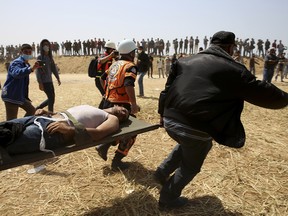 Palestinian protesters and civil defence evacuate a wounded youth during clashes with Israeli troops along Gaza's border with Israel, east of Khan Younis, Friday, April 6, 2018.