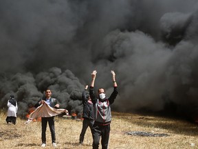 Palestinian protesters call others to bring more tires to burn during clashes with Israeli troops along Gaza's border with Israel, east of Khan Younis, Gaza Strip, Friday, April 6, 2018.