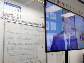 French President Emmanuel Macron appears on a television screen during a televised interview in Berd'huis, south of Paris, Thursday, April 12, 2018. Macron is appearing on national television Thursday to respond to the daily concerns of the French and defend his economic policies and tax changes, which he says are aimed at modernizing the country. At left is a text written by pupils and reading: Mister President, we are happy to lend you our classroom. Can you please sign our sheet. Many thanks. The schoolchildren.