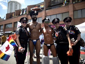 Revellers pose for a photos with police officers at the annual Pride Parade in Toronto on Sunday, July 3, 2016.