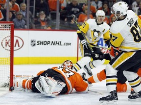 The puck bounces back out behind Philadelphia Flyers goalie Brian Elliott on a power-play goal by Pittsburgh Penguins' Evgeni Malkin (71) as Sidney Crosby, right, watches during the first period in Game 4 of an NHL first-round hockey playoff series Wednesday, April 18, 2018, in Philadelphia.