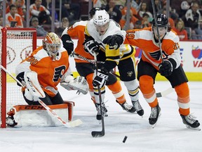 Philadelphia Flyers goalie Michal Neuvirth, left, watches Pittsburgh Penguins' Jake Guentzel, center, and Flyers' Nolan Patrick, right, chase the puck through the crease during the third period in Game 4 of an NHL first-round hockey playoff series Wednesday, April 18, 2018, in Philadelphia. The Penguins won 5-0.
