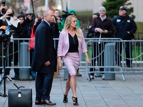 FILE - In this April 16, 2018, file photo, porn actress Stormy Daniels, accompanied by her attorney, Michael Avenatti, left, leaves federal court, in New York. A federal judge is set to hear arguments about whether to delay the case of Daniels, who claims she had an affair with President Donald Trump, after federal agents raided the president's personal lawyer's office and residence. U.S. District Judge James Otto will hold the hearing Friday, April 20, in Los Angeles.